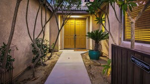 Un edificio residenziale con una porta gialla, un vialetto in cemento e un cartello con la scritta 'No Soliciting'.