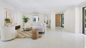 A modern living room with a white sofa, a round coffee table, and a patterned rug. - Riviera Road Miami - 4BRM Dual Villa (Miami)