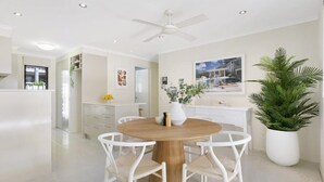 A modern kitchen with white cabinetry, a wooden dining table, and a ceiling fan. - Riviera Road Miami - 4BRM Dual Villa (Miami)