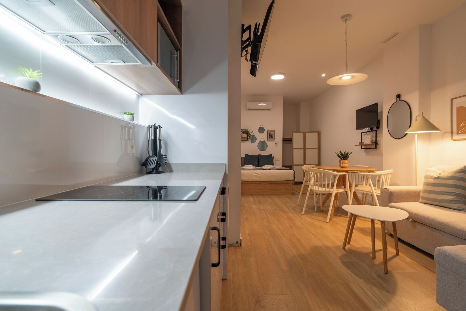Une cuisine moderne dotée d’une cuisinière intégrée, de meubles de rangement en bois et d’un coin repas avec une table et des chaises.