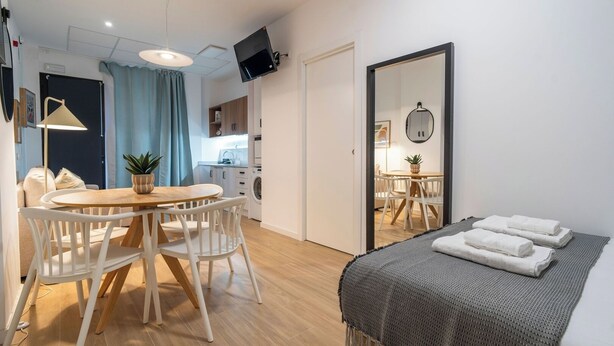 Un espace de vie compact comprenant un coin repas, une kitchenette et un lit avec des serviettes.