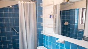 Ein Badezimmer mit blauen Fliesen, einer weißen Toilette, einem Waschbecken und einer Duschvorhang.