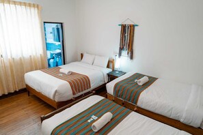 A hotel room with two beds, a wooden floor, a bathroom with a mirror, and a wall-mounted decoration. - Natural B&B Guest House (Cusco)
