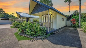 A modern house with a sloped roof, a covered porch, and a well-maintained garden with tropical plants. - Hideaway Mission Beach Village (Mission Beach)