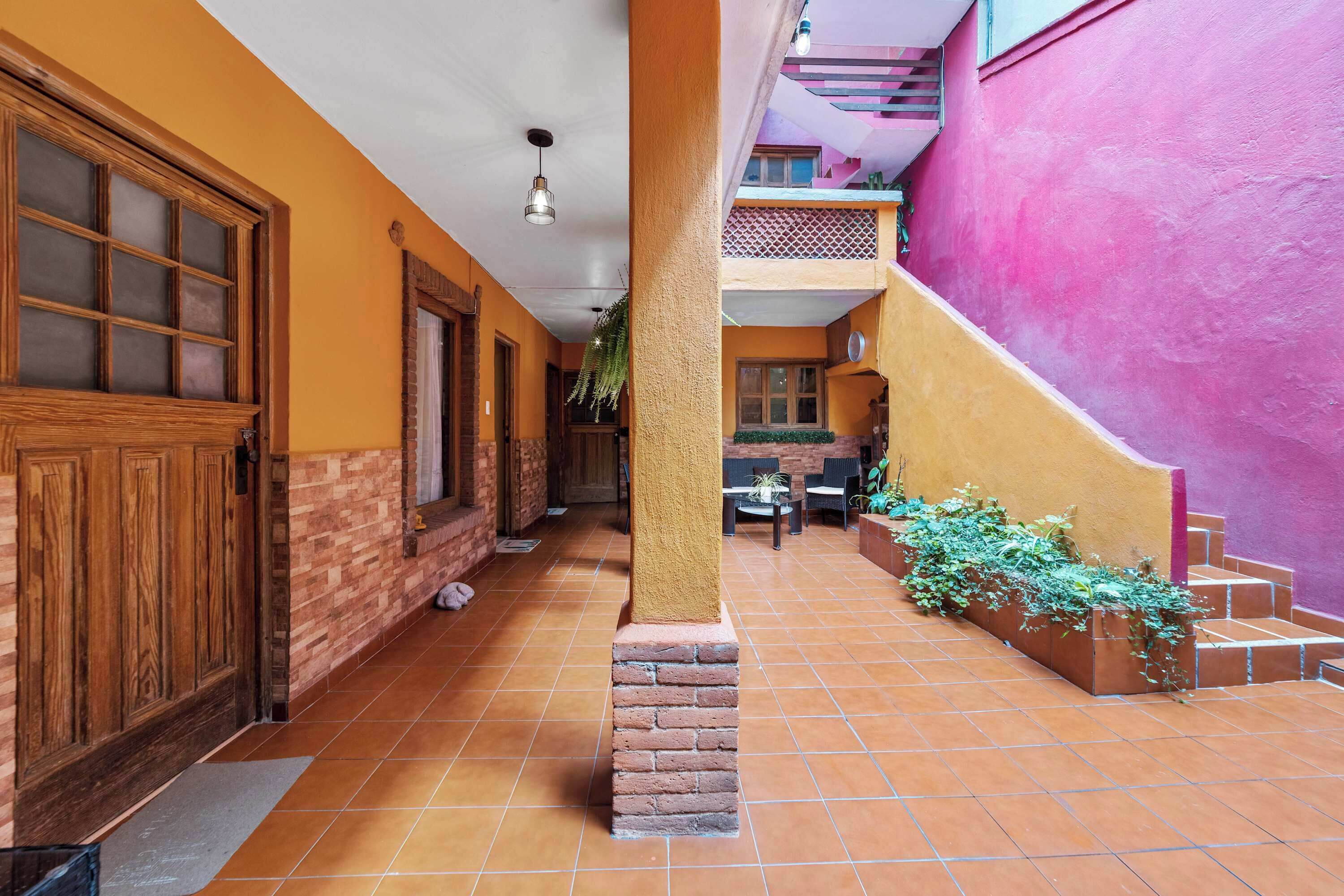 Un pasillo con puerta de madera, paredes de ladrillo y piso de baldosas.