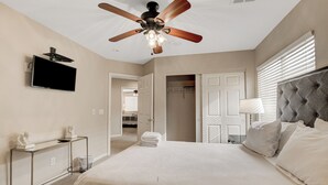A bedroom with a bed, a ceiling fan, a TV, a bedside table, and a closet. - Close to Airport, Stadium, and Strip. Villa with Amazing Pool and BBQ/Bar Area (Las Vegas)