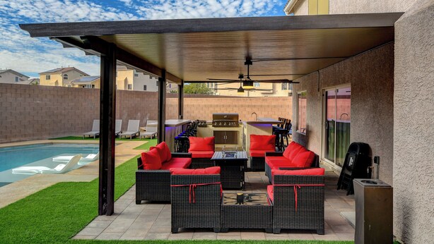 An outdoor patio with wicker furniture, a barbecue grill, and a swimming pool.