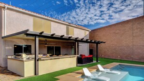 A backyard with a pool, a barbecue area, and a covered patio.