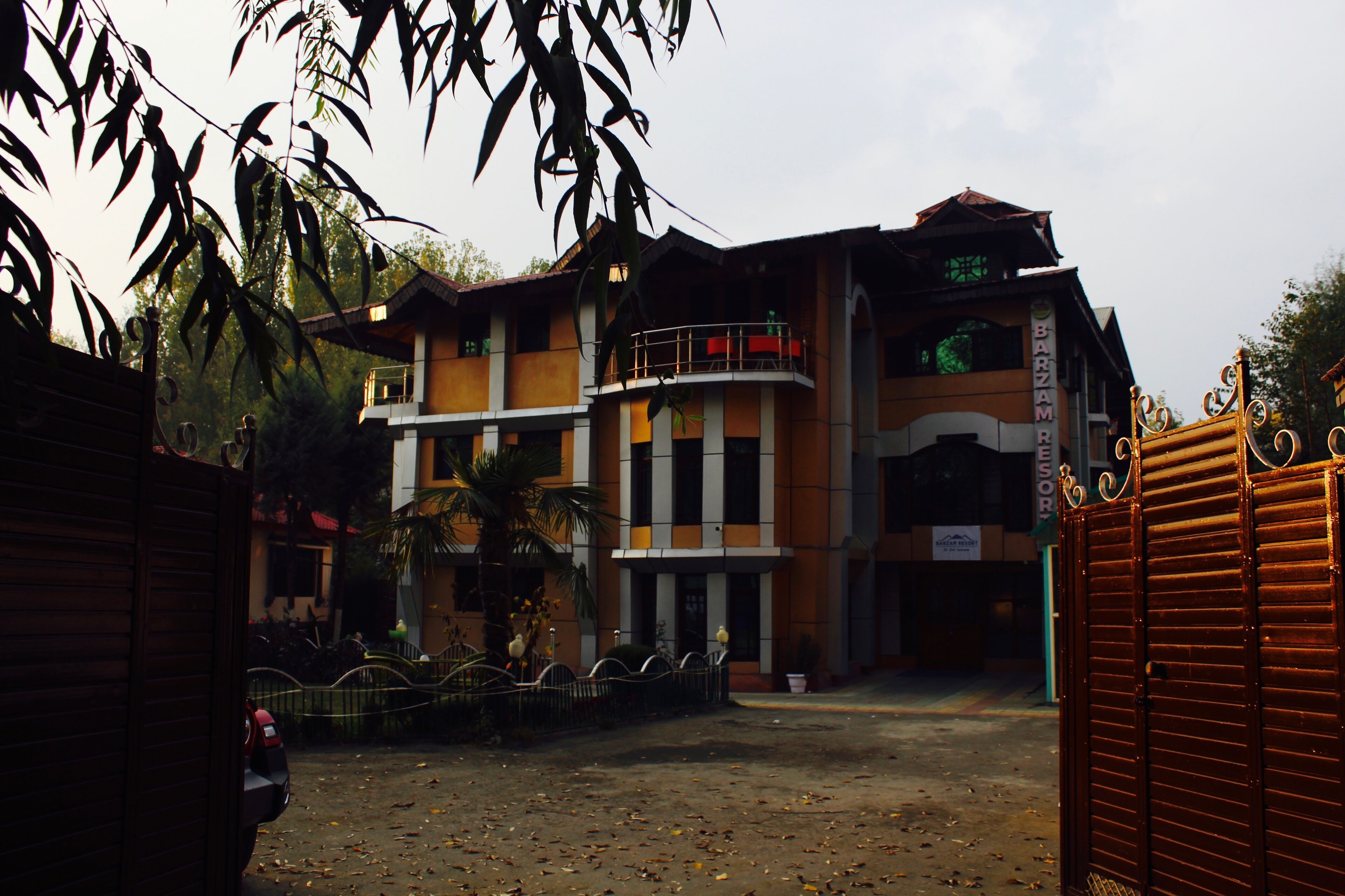 A multi-story building with a gated entrance, a balcony, and a sign indicating a restaurant.