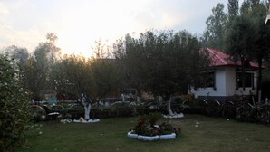 A residential garden with a small house, a fenced area, and a variety of plants. -  Barzam Lake View Resort (Srinagar)
