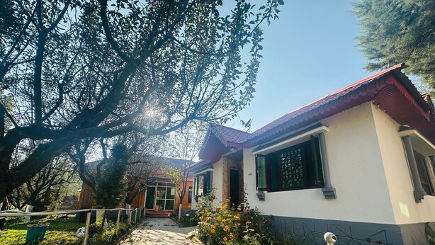 A pathway leading to a house with a red roof and white walls, surrounded by greenery and trees. -  Barzam Lake View Resort (Srinagar)
