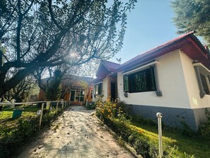 A pathway leading to a house with a red roof and white walls, surrounded by greenery and trees. -  Barzam Lake View Resort (Srinagar)