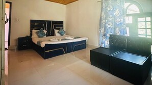 A bedroom with a bed, a desk, a ceiling fan, and a window with curtains. -  Barzam Lake View Resort (Srinagar)