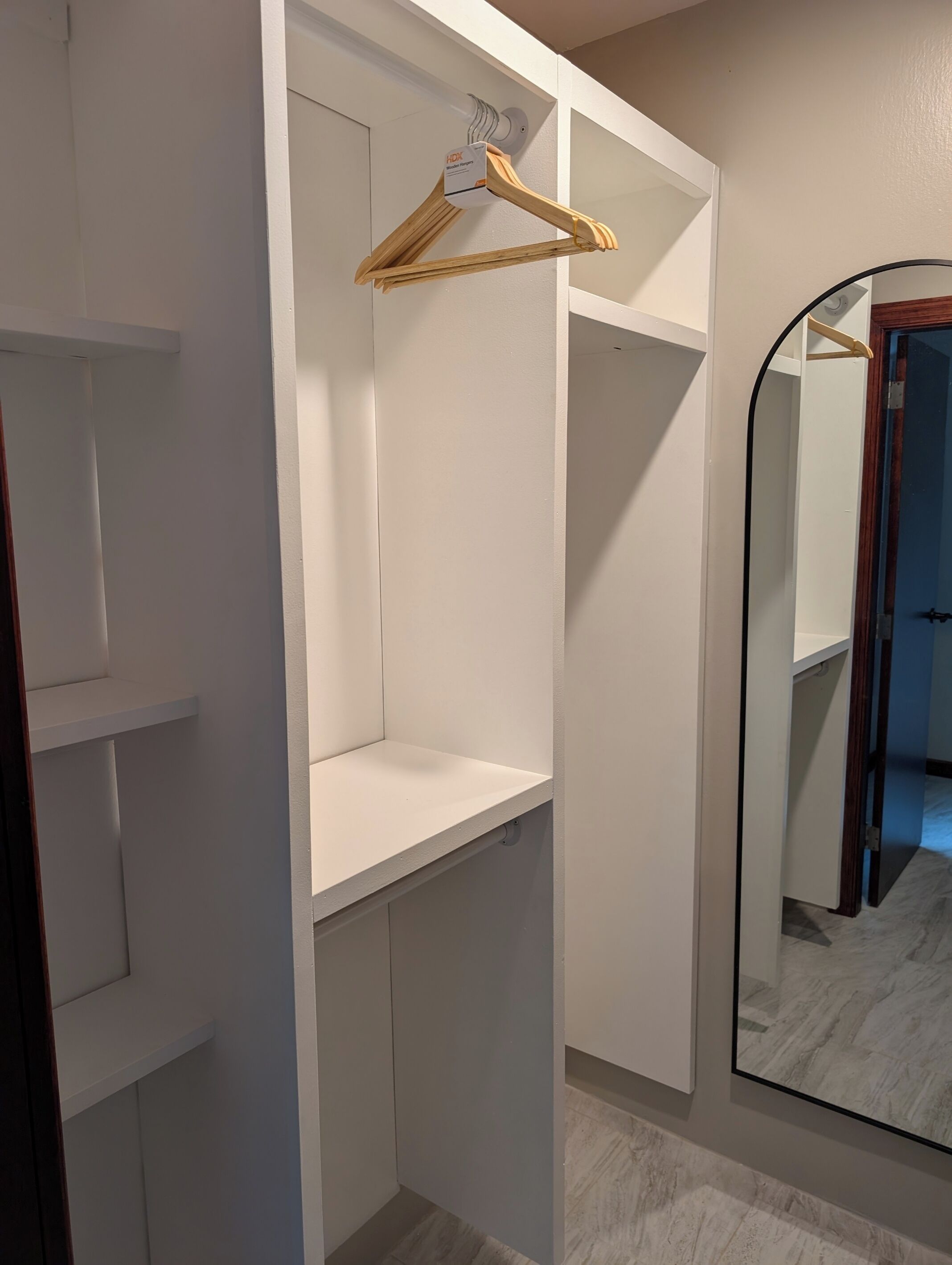 Un dressing avec des étagères ouvertes et une tringle pour suspendre les vêtements.