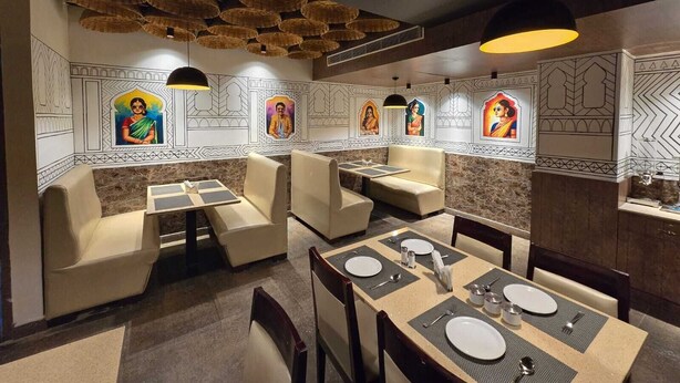 Un restaurant doté de tables hautes et de banquettes, décoré avec des œuvres d’art murales traditionnelles et des paniers suspendus.