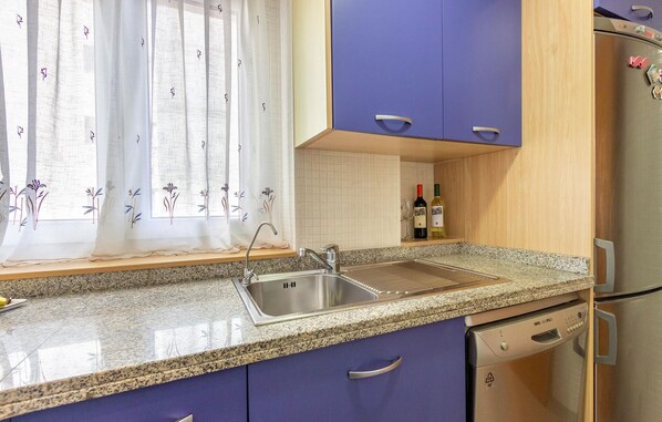 A kitchen with a granite countertop, stainless steel sink, and a dishwasher.