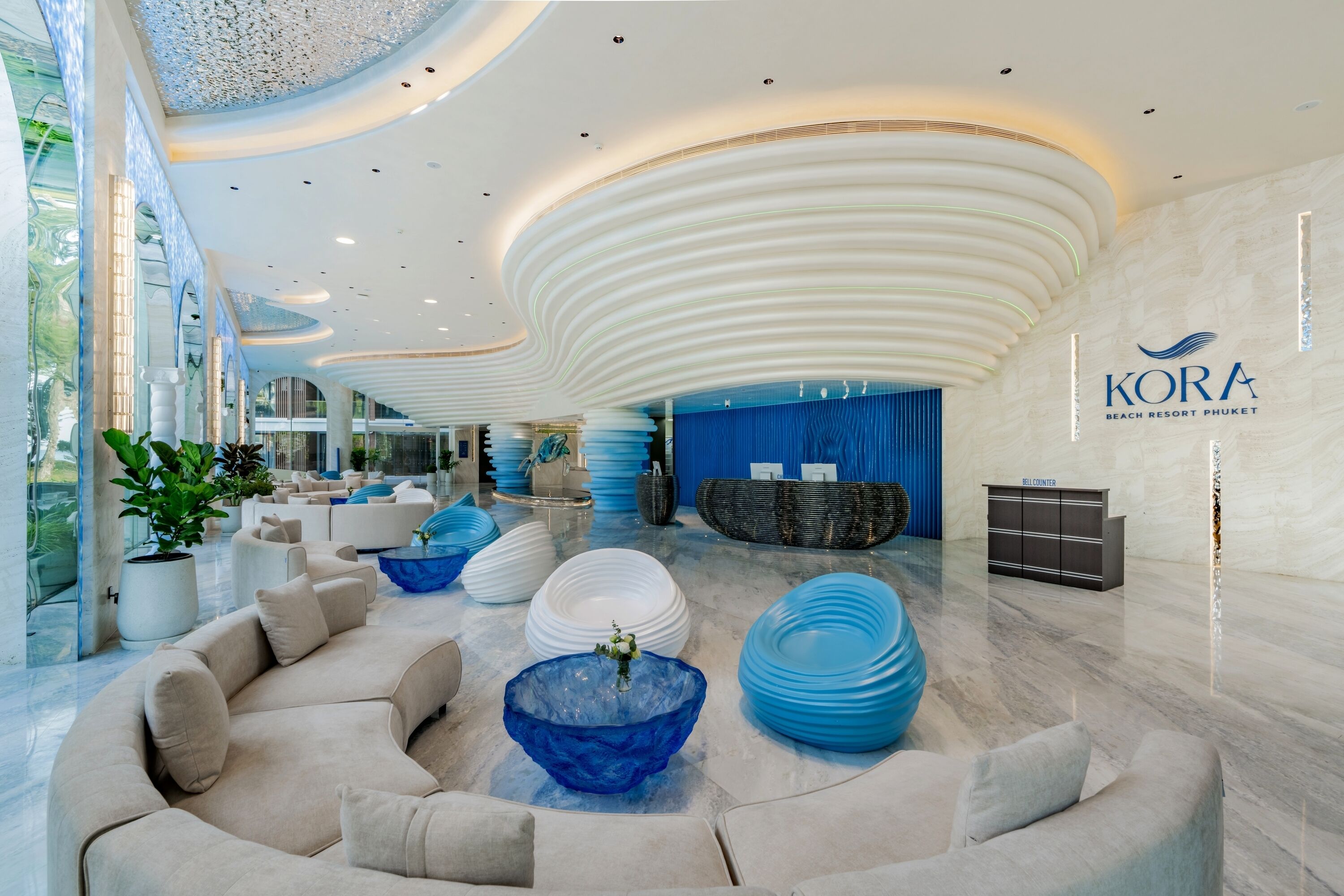 A modern lobby with a curved ceiling, a reception desk, and a seating area with a blue glass bowl centerpiece.