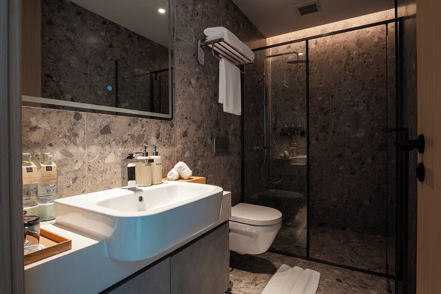 A modern bathroom with a large sink, toilet, and glass-enclosed shower.