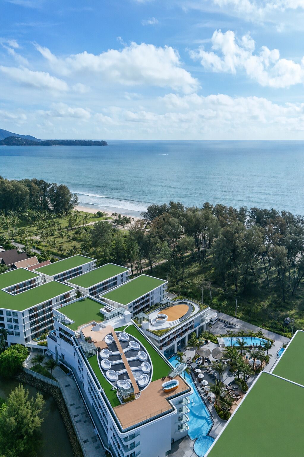 A resort with multiple buildings, a swimming pool, and a view of the ocean.