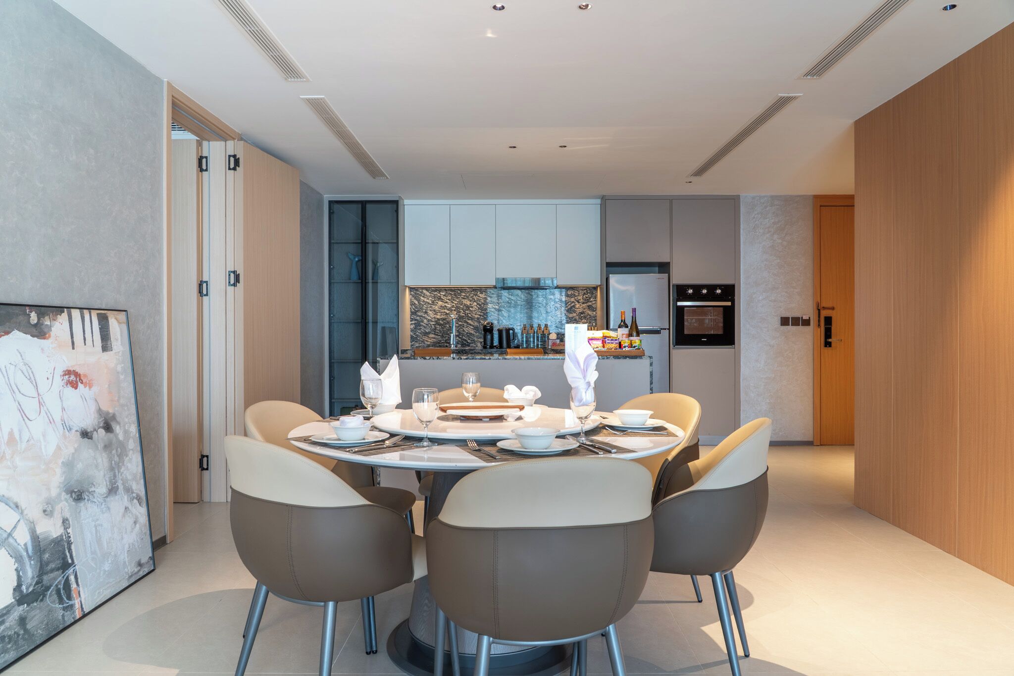 A modern dining area with a round table set for four, surrounded by contemporary chairs.