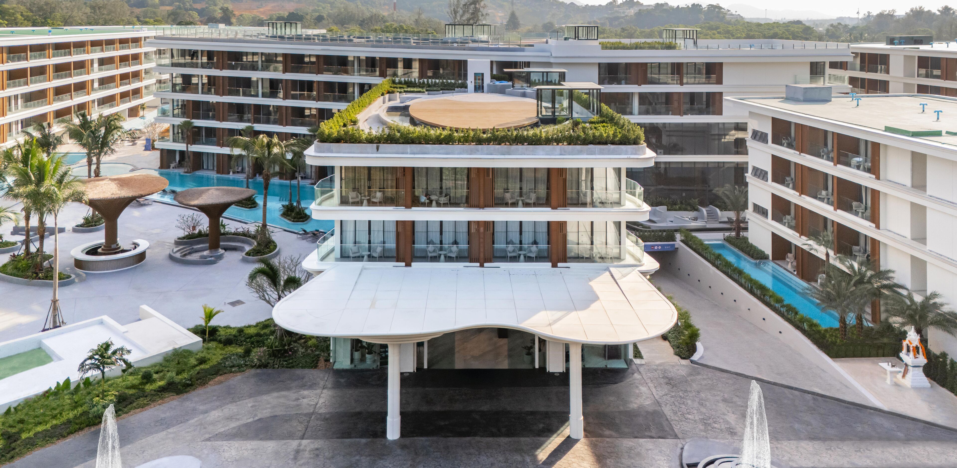 A multi-story hotel with a rooftop garden, a swimming pool, and a landscaped courtyard.