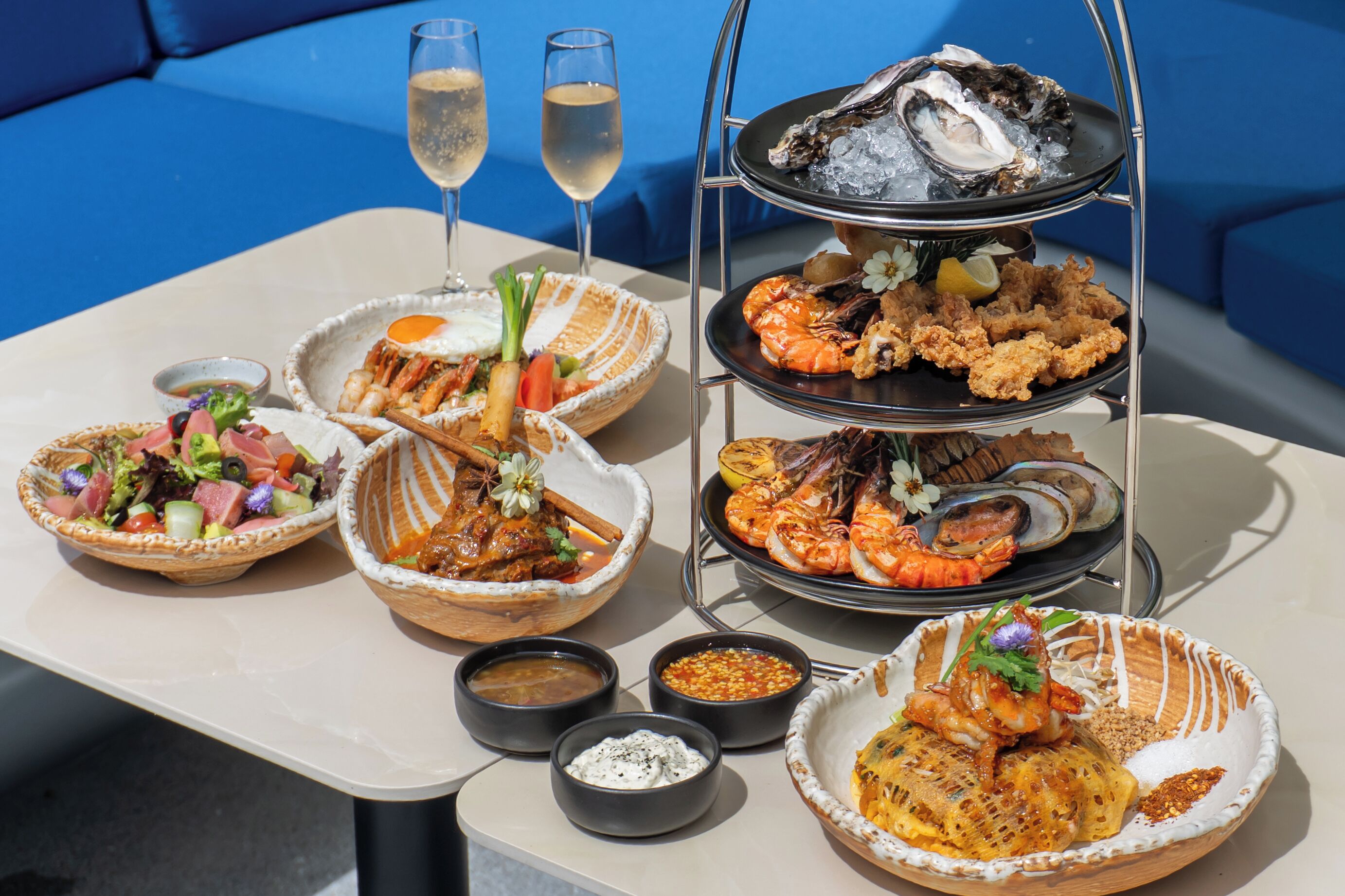 Una mesa con diversos platos de mariscos, dos copas de champán y una presentación escalonada de mariscos.