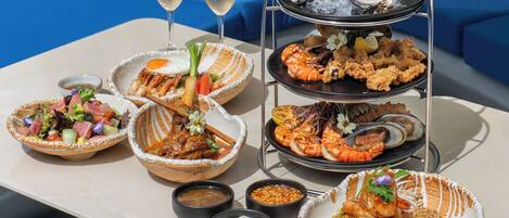Una mesa con diversos platos de mariscos, dos copas de champán y una presentación escalonada de mariscos.