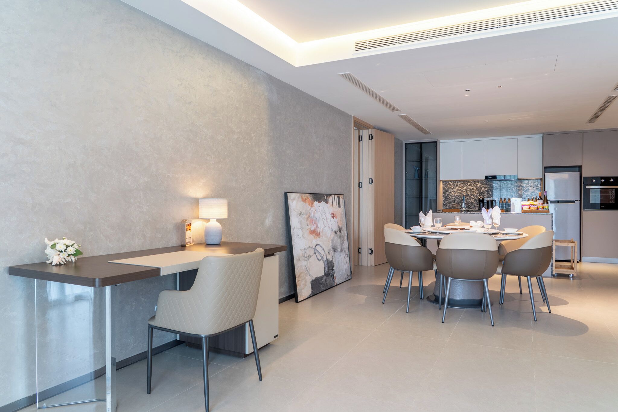 A modern kitchen with a dining area, featuring a central island, chairs, and a table set for dining.