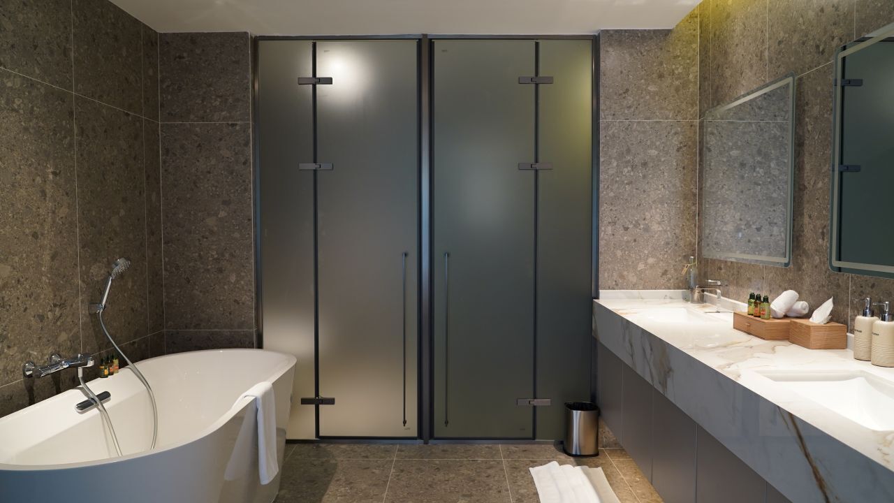A modern bathroom with a freestanding bathtub, two vanity sinks, a large mirror, and a shower enclosure.