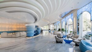 A spacious lobby with modern seating, a unique blue and white design, and large windows offering natural light. - Kora Beach Resort Phuket (Choeng Thale)