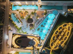 An aerial view of a resort with multiple swimming pools, sun loungers, and a large circular water feature. - Kora Beach Resort Phuket (Choeng Thale)