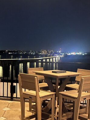 Relax in this waterfront seating area with a city view, featuring a book and comfortable seating.