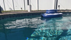A clear pool with visible ripples and a blue inflatable float. - Luxurious Home - Concierge - Private Saltwater Pool - Expansive Home and Yard (Cape Coral)