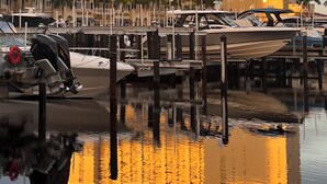 Et stort hotel med et tydeligt "Westin" skilt, der spejles i stille vand, omgivet af fortøjede både og palmer.