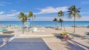 A beach with palm trees, sun loungers, and a clear blue sky. - Sunset Oceanfront Villa (Hollywood)
