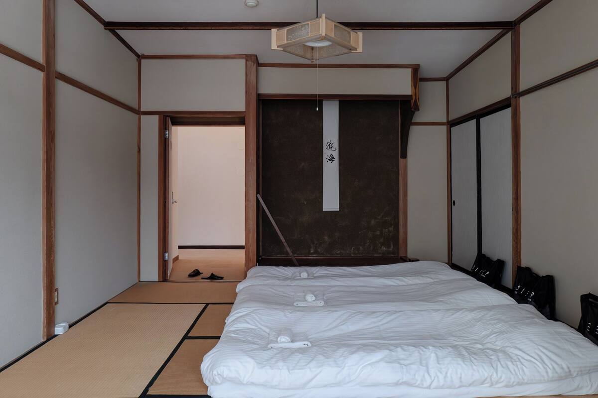 A traditional Japanese-style room with tatami flooring, a large bed, and a sliding door.