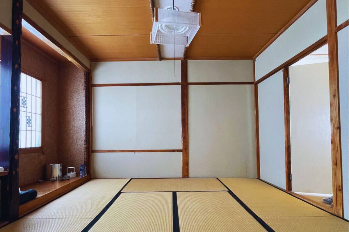 A tatami mat room with sliding doors, a ceiling fan, and a window with a view.