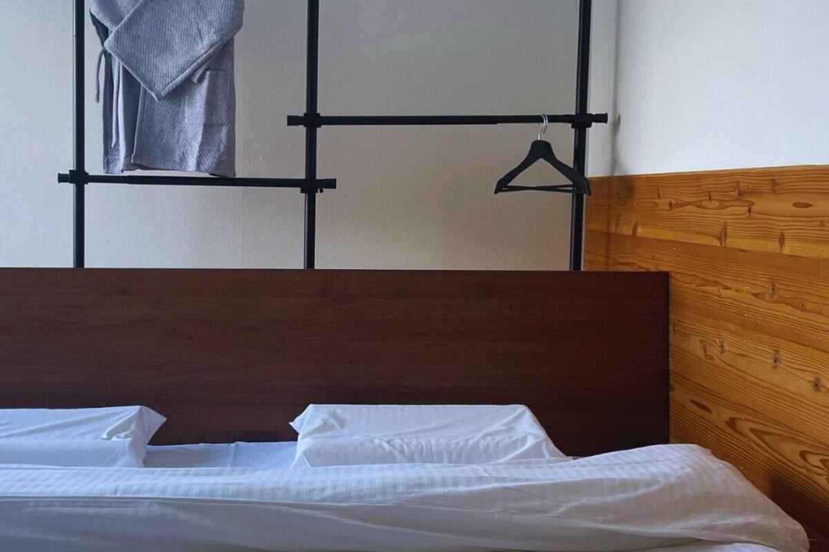 A neatly made bed with white linens in a room with a wooden headboard and a wooden wall panel.