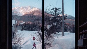 Une pièce dotée d’une grande fenêtre donnant sur un paysage enneigé et des montagnes.