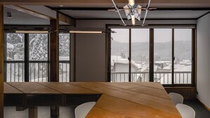 Une salle de conférence dotée d’une grande table et de chaises, de larges fenêtres offrant une vue sur un paysage enneigé et d’un luminaire moderne au plafond.