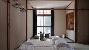 Une pièce de style japonais traditionnel, avec un sol recouvert de tatamis, une petite table basse avec un coussin et une porte coulissante donnant sur une autre pièce.