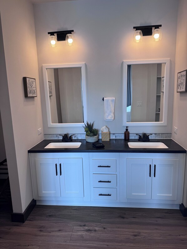 Een moderne badkamer met twee wastafels, een grote spiegel en een handdoekhouder.