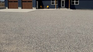 A two-story building with a garage, a covered porch, and a gravel driveway.