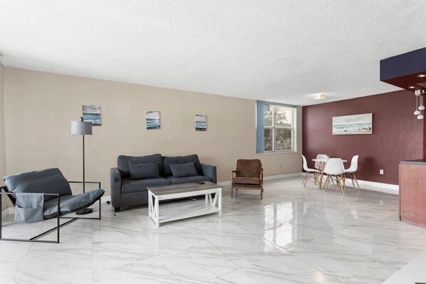 Ein modernes Wohnzimmer mit Sofa, Sessel, Couchtisch und Essbereich.