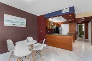 Eine moderne Küche mit Holzschränken, einem Edelstahlkühlschrank und einer Marmorarbeitsplatte.