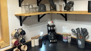 Une cuisine avec des étagères en bois, une machine à café et divers ustensiles de cuisine.