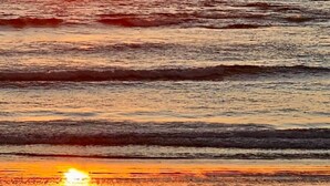 Una playa con olas y un atardecer.