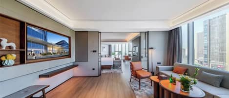 Una habitación de hotel moderna con un ventanal grande, un sofá, una mesita de café y un escritorio.