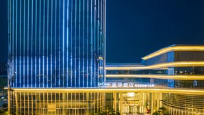 A modern hotel with a glass facade and illuminated signage. - UrCove by Hyatt Weifang City Center (Weifang)