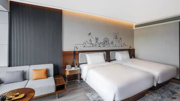 A hotel room with two beds, a sofa, a small table with a tray, a nightstand, and a wall mural.